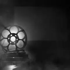 Stara taśma filmowa mk2, oświetlona od tyłu, unosi się w dymie, tworząc magiczną atmosferę kina.