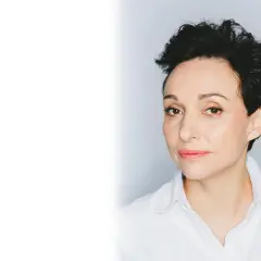 Kobieta z krótkimi, ciemnymi włosami, w białej koszuli. To reżyserka filmu "Moje córki krowy".