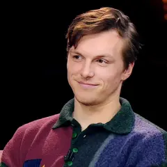 Uśmiechnięty Tomasz Włosok, aktor znany z wielu filmów, w kolorowym swetrze.