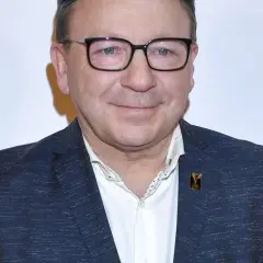 Zbigniew Zamachowski w garniturze i okularach, znany z wielu polskich filmów.