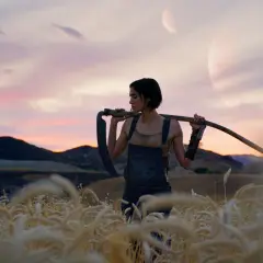 Kobieta z kosą na ramieniu na tle zachodzącego słońca i dwóch księżyców. Klimat jak z filmów Zacka Snydera.