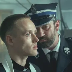 Młody ksiądz i policjant w mundurze, w tle widać innych mężczyzn. Scena z filmu "Boże Ciało", którego reżyserem jest Jan Komasa.