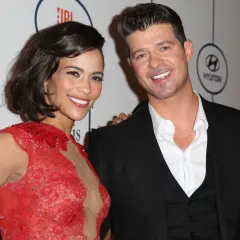 Paula Patton w czerwonej sukni i Robin Thicke na gali. Paula Patton znana z wielu filmów, uśmiecha się do aparatu.