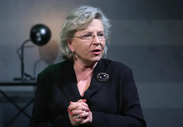 Krystyna Janda w czarnej kreacji, z broszą i okularach, jakby opowiadała o swoich filmach.