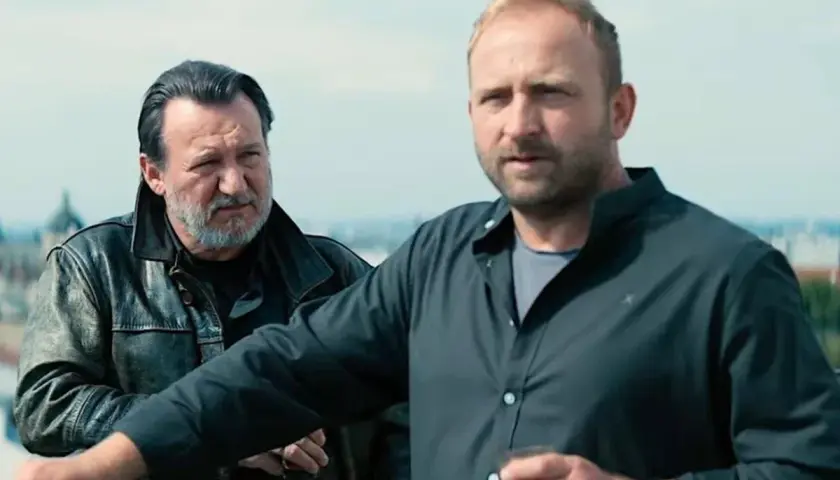 Dwóch mężczyzn na dachu, jeden w skórzanej kurtce, drugi w czarnej koszuli. Scena z jednego z juliusz machulski filmów.