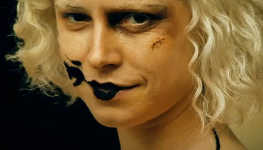 Blondynka z makijażem jak z nowych horrorów, czarne usta i blizna na policzku.