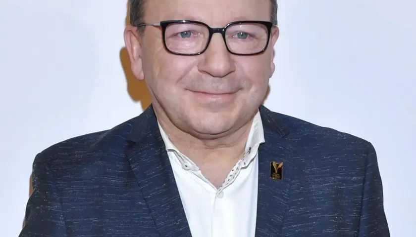 Zbigniew Zamachowski w garniturze i okularach, znany z wielu polskich filmów.