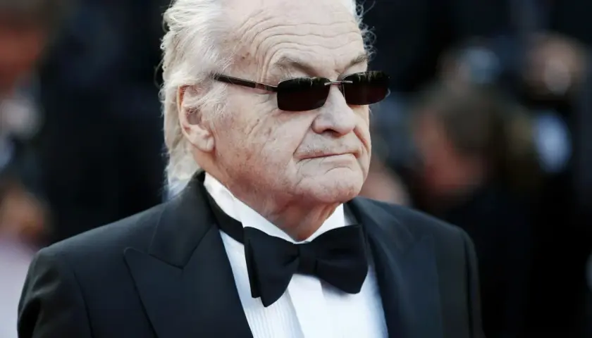 Jerzy Skolimowski w smokingu i okularach przeciwsłonecznych, ikona polskiego kina.