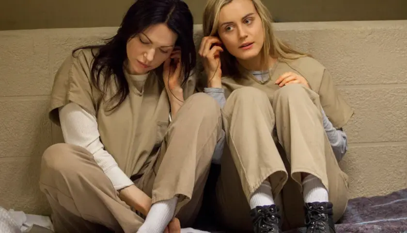 Dwie kobiety w więziennych strojach słuchają muzyki. To scena z serialu "Orange Is the New Black", popularnego filmu o lesbijkach na Netflix.