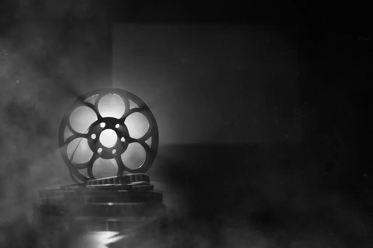 Stara taśma filmowa mk2, oświetlona od tyłu, unosi się w dymie, tworząc magiczną atmosferę kina.