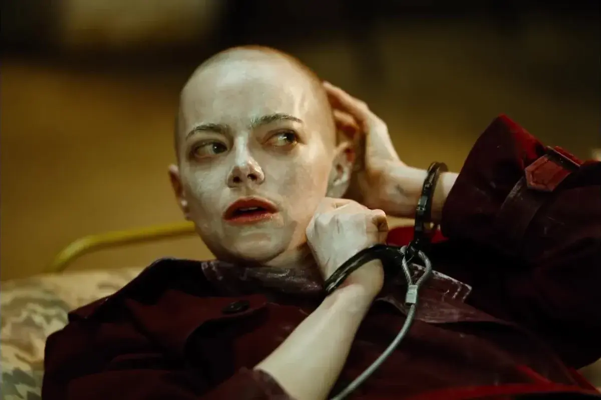 Emma Stone w kajdankach, z ogoloną głową i makijażem, jak w filmach Yorgosa Lanthimosa.