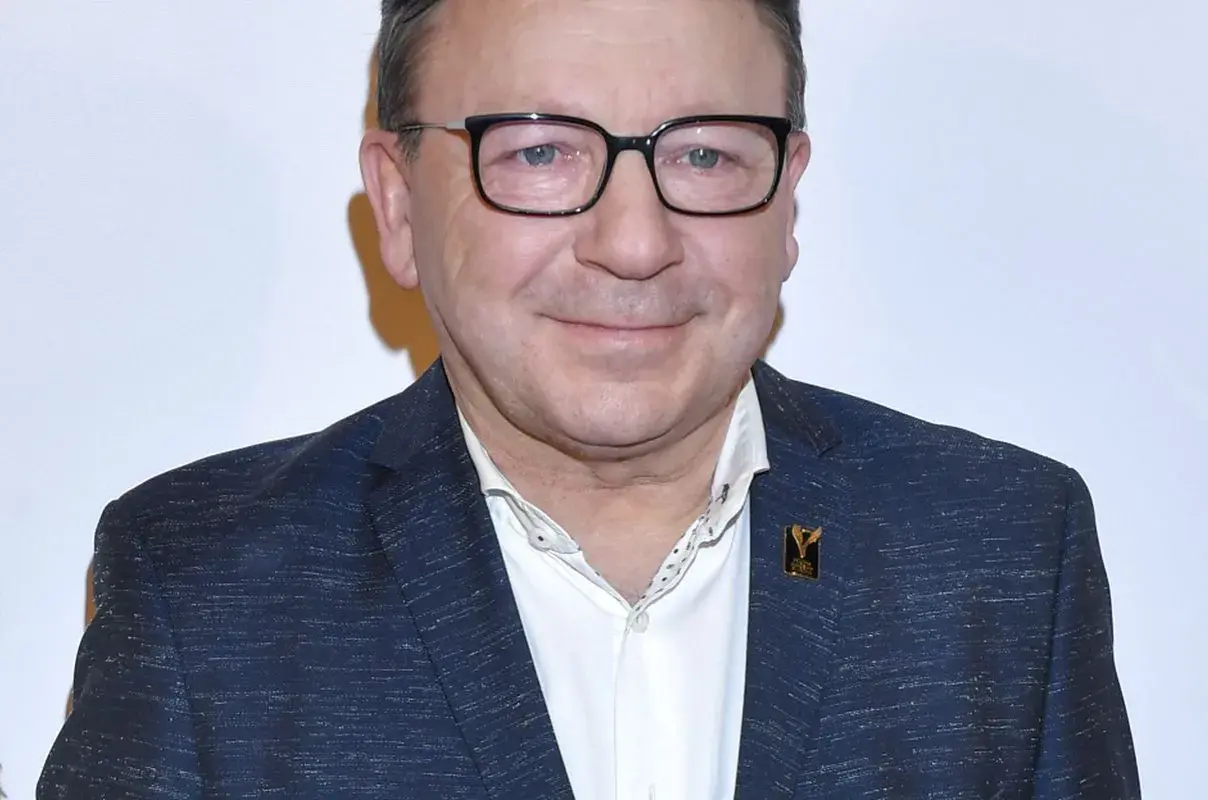 Zbigniew Zamachowski w garniturze i okularach, znany z wielu polskich filmów.