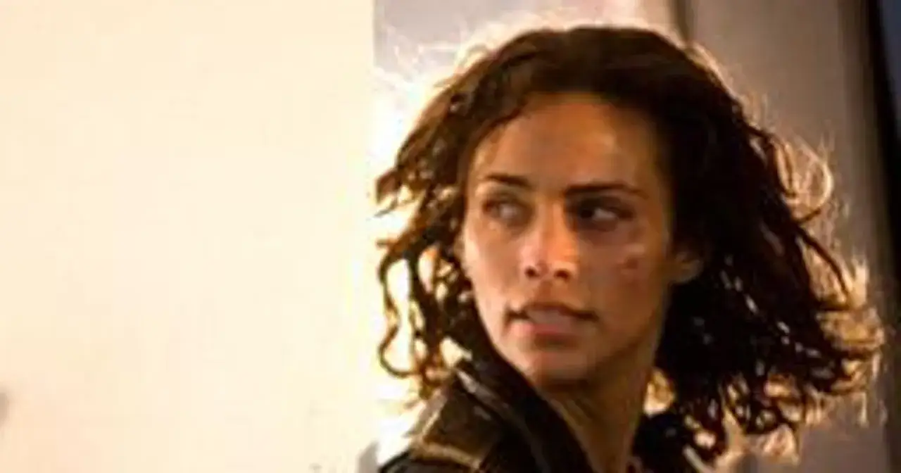 Paula Patton w filmach, z zaciekawieniem spogląda w bok, z widocznymi śladami walki na twarzy.