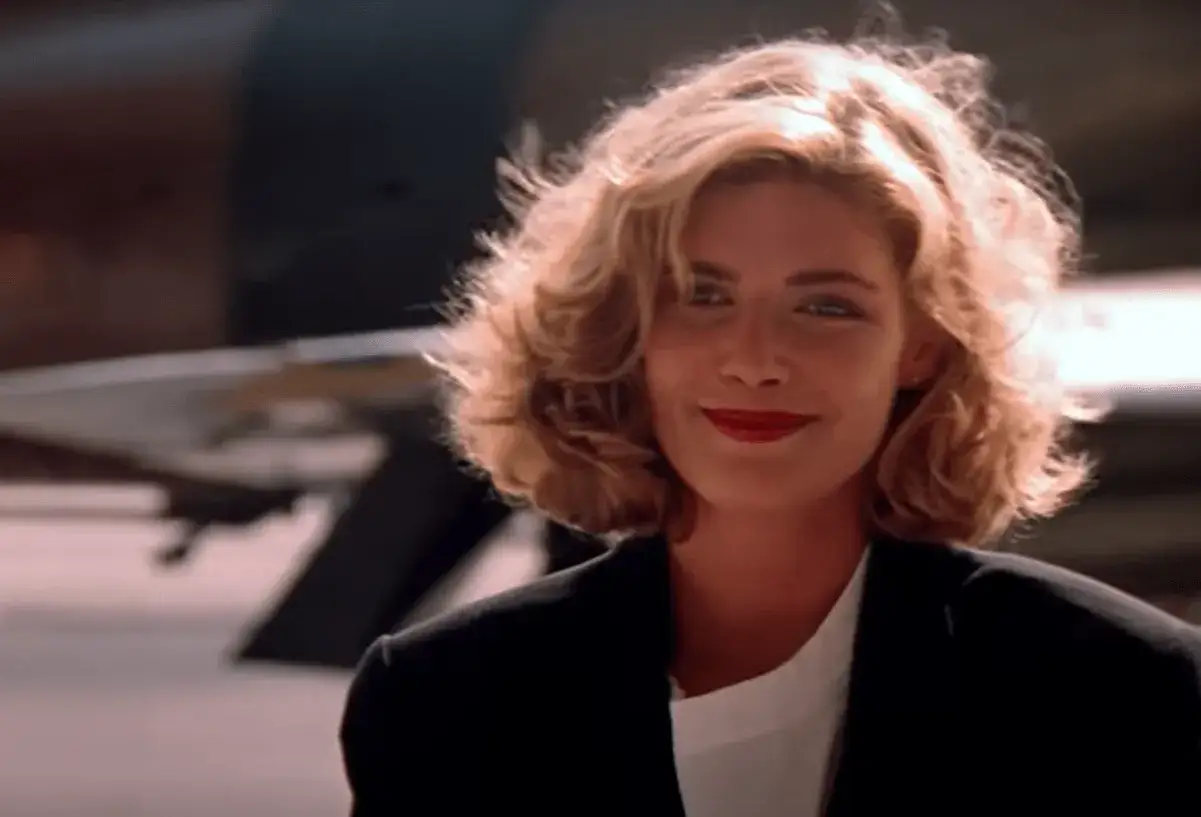 Uśmiechnięta Kelly McGillis w czarnej marynarce, przypominająca jej role w kultowych filmach.