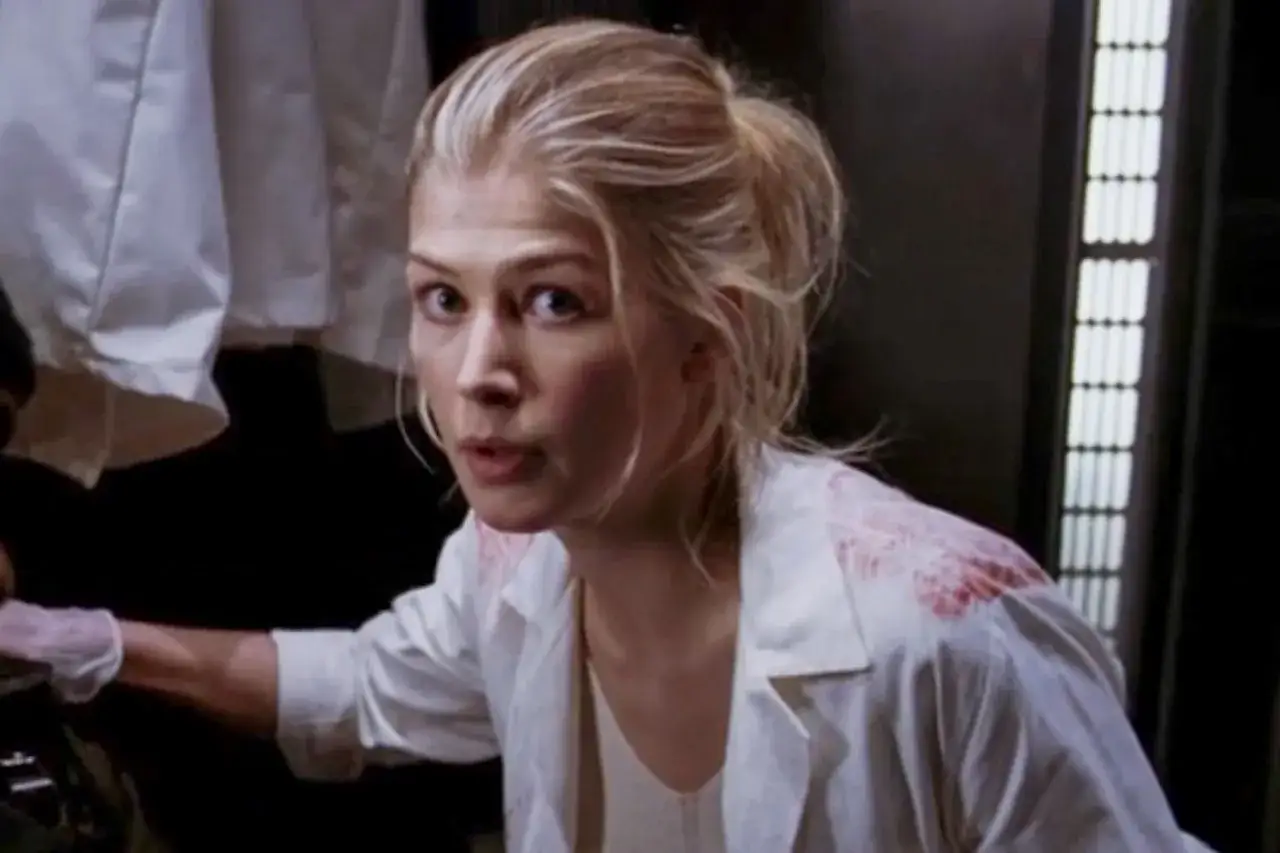 Rosamund Pike w białej koszuli z plamami krwi, w scenie z jednego z jej filmów.