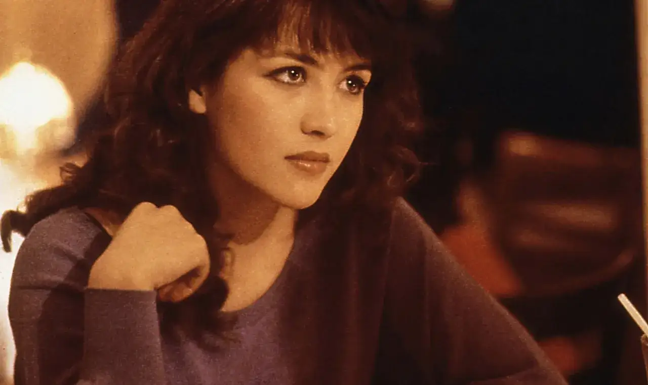Sophie Marceau w filmach, z burzą brązowych włosów i spojrzeniem pełnym zadumy, przypomina scenę z jej kultowych ról.