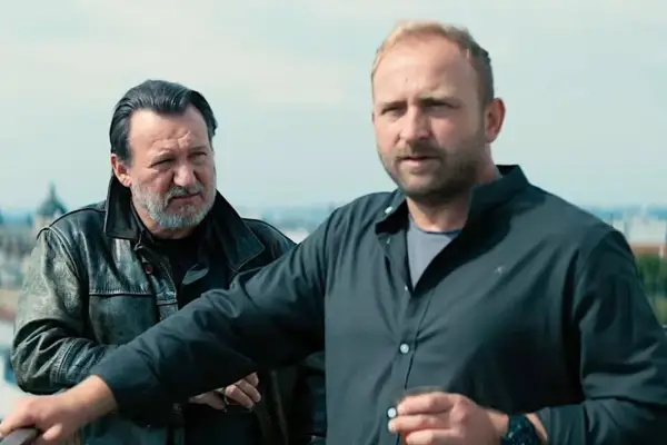 Dwóch mężczyzn na dachu, jeden w skórzanej kurtce, drugi w czarnej koszuli. Scena z jednego z juliusz machulski filmów.